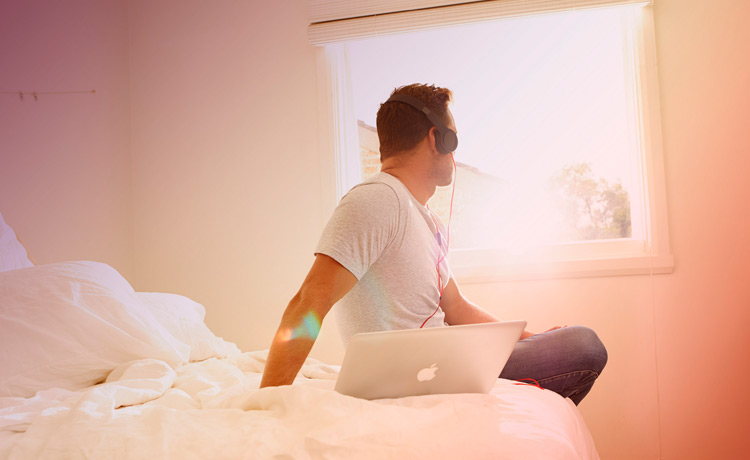 Man sitting on bed with laptop
